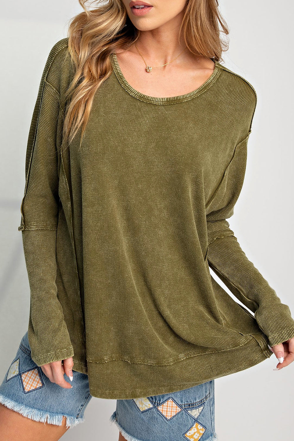 A stylish green long sleeve top with raw seams and a relaxed fit, perfect for casual wear.
