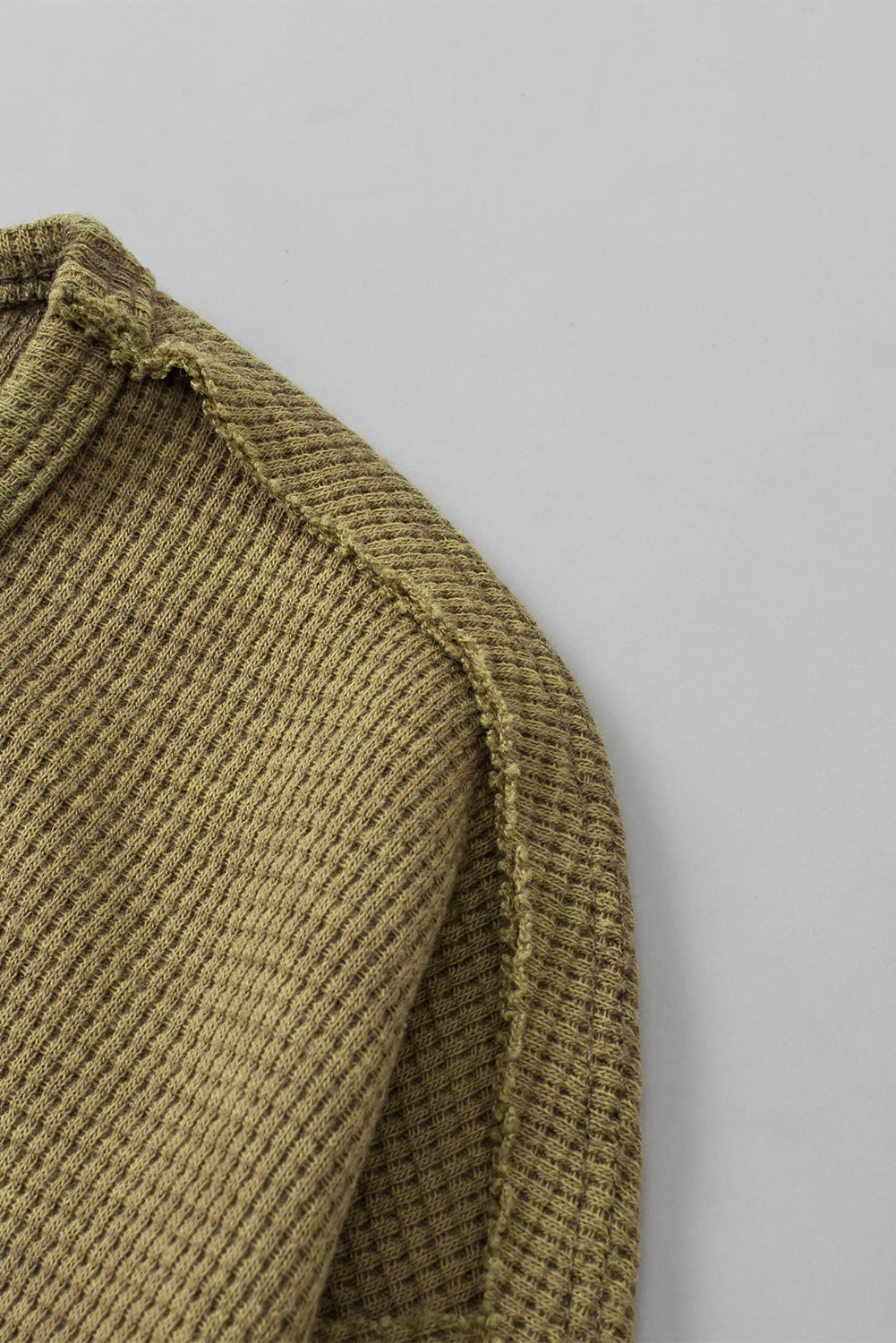 A stylish green long sleeve top with raw seams and a relaxed fit, perfect for casual wear.