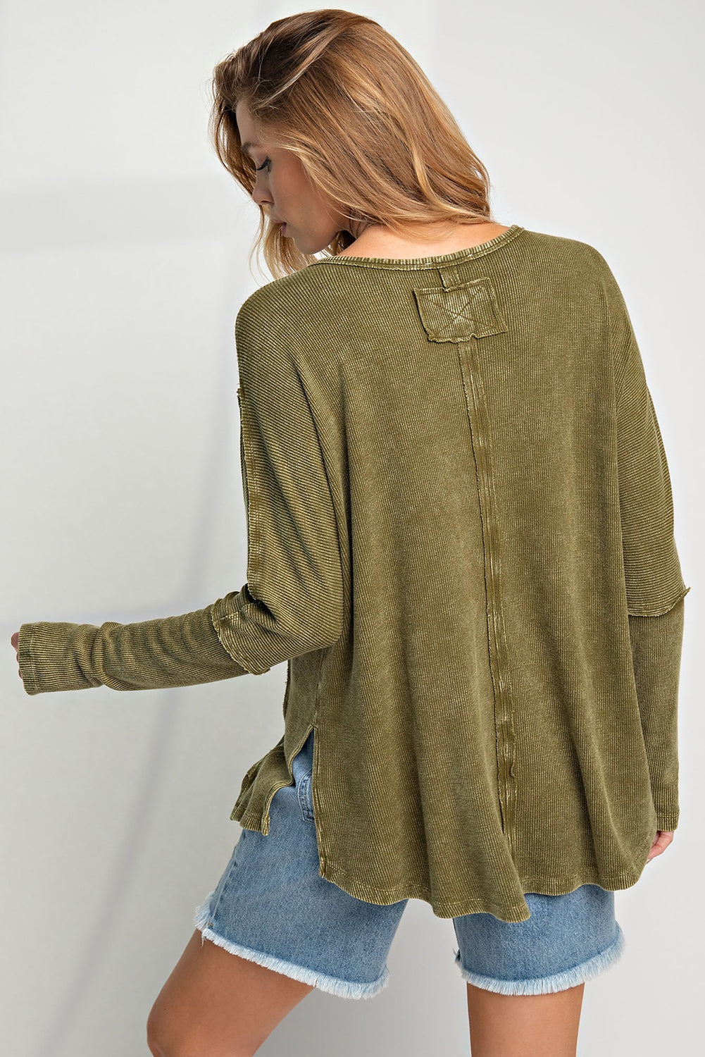 A stylish green long sleeve top with raw seams and a relaxed fit, perfect for casual wear.