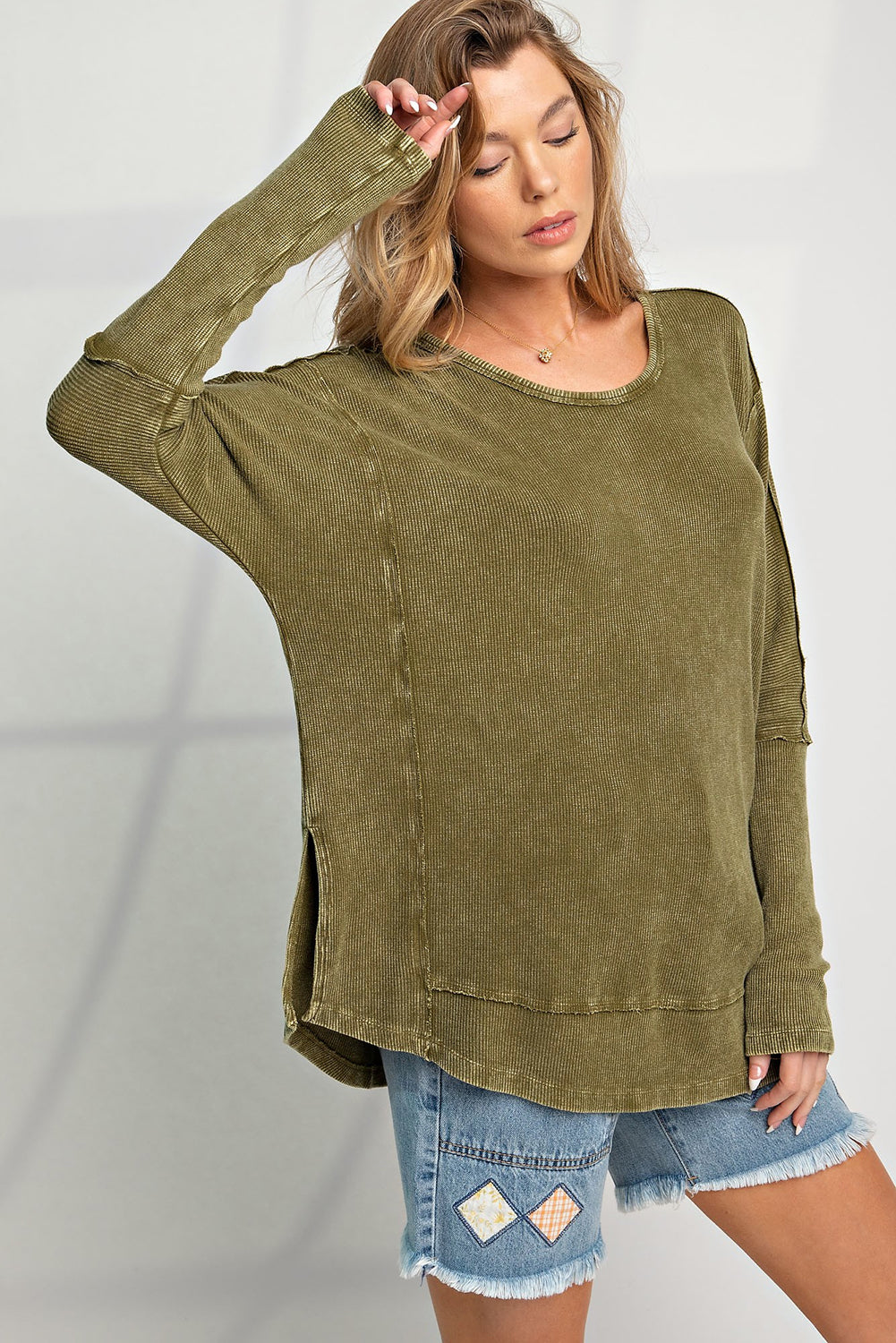 A stylish green long sleeve top with raw seams and a relaxed fit, perfect for casual wear.