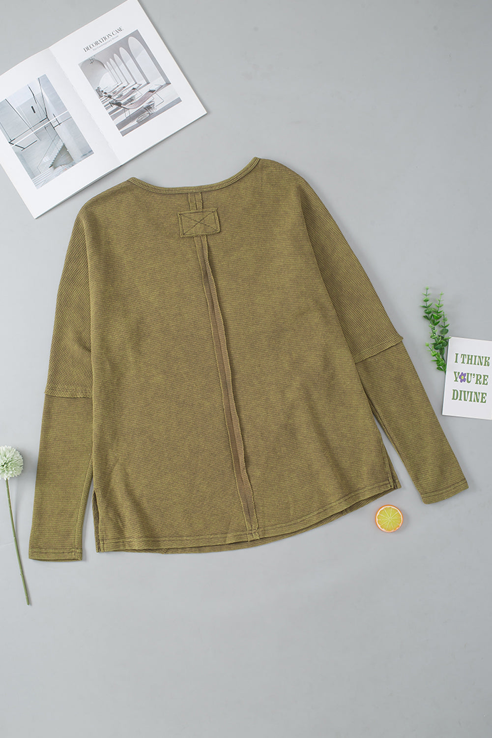 A stylish green long sleeve top with raw seams and a relaxed fit, perfect for casual wear.