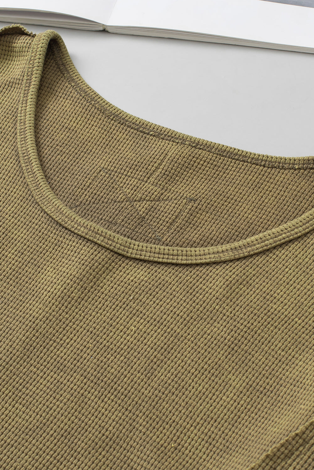 A stylish green long sleeve top with raw seams and a relaxed fit, perfect for casual wear.