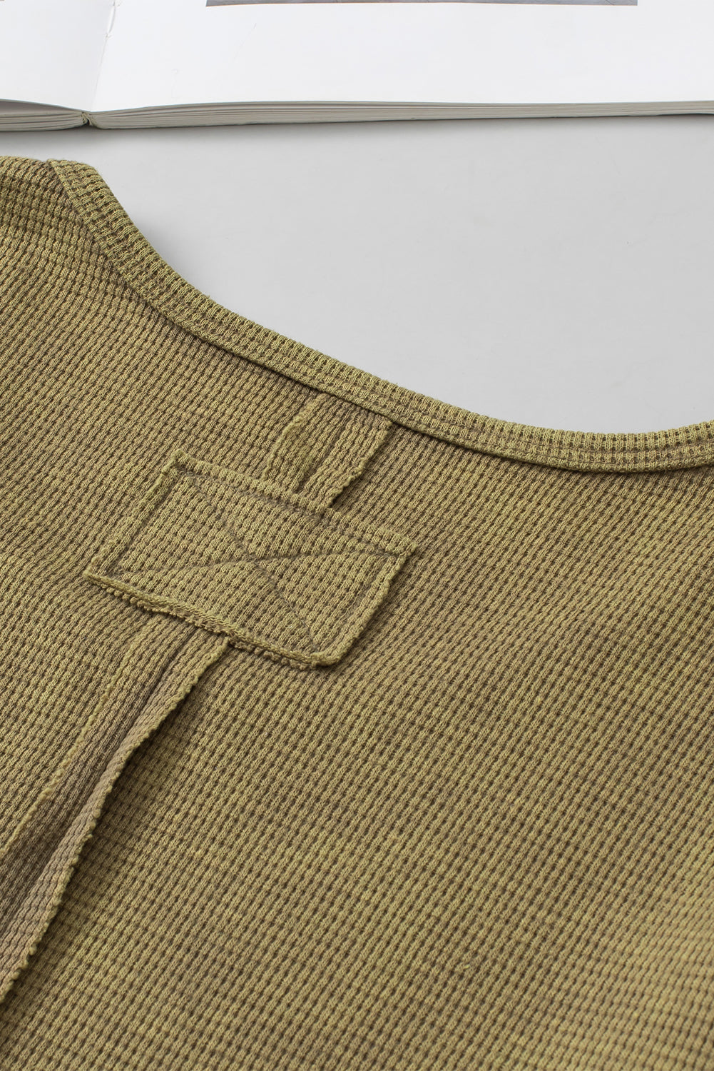 A stylish green long sleeve top with raw seams and a relaxed fit, perfect for casual wear.