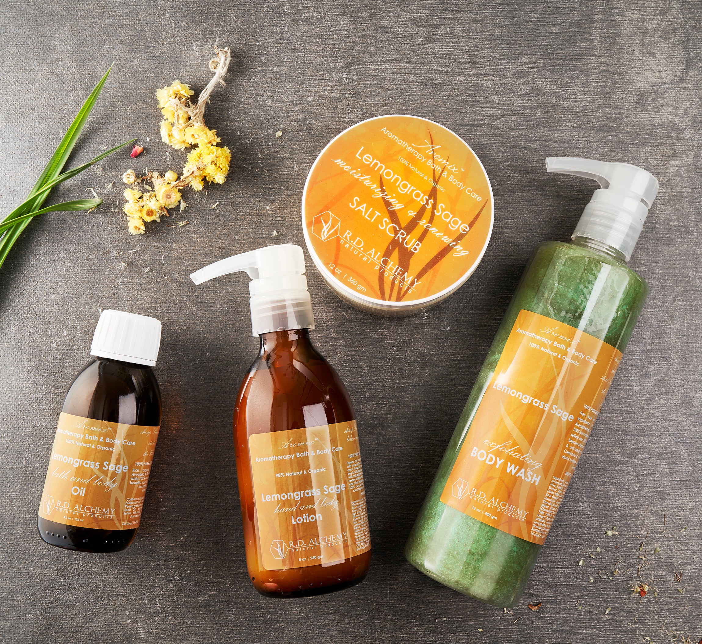 Lemongrass Sage Sea Salt Body Scrub in a clear jar with a wooden spoon, showcasing its textured scrub consistency and earthy color.