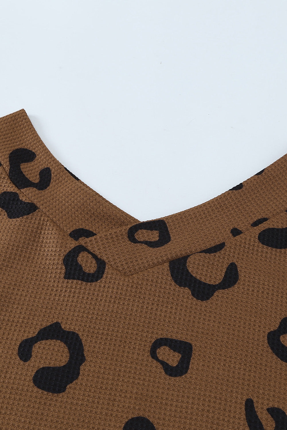 A stylish leopard print top featuring a side split design, V-neckline, and long sleeves, perfect for casual wear.