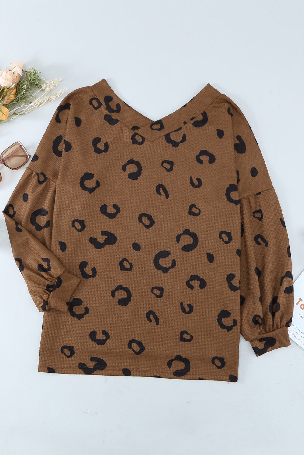 A stylish leopard print top featuring a side split design, V-neckline, and long sleeves, perfect for casual wear.