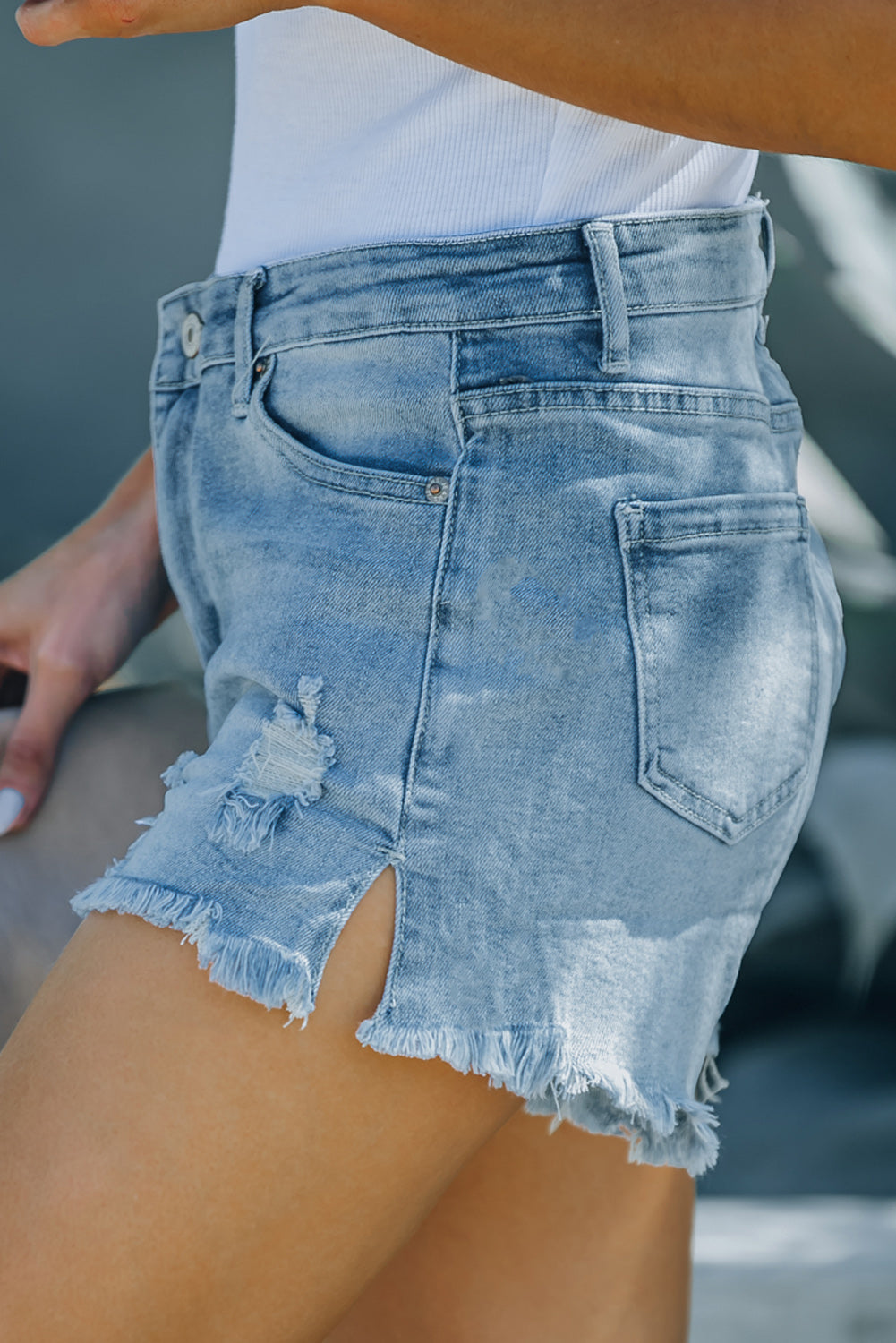 Light blue distressed ripped denim shorts with pockets, featuring a frayed hemline and high rise fit, perfect for summer wear.