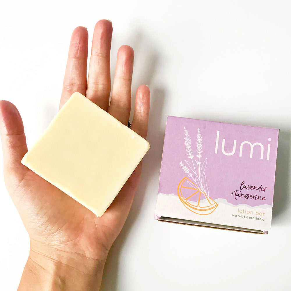 A solid lotion bar in a square shape, featuring a sweet lavender citrus scent, placed on a wooden surface with natural elements around it.
