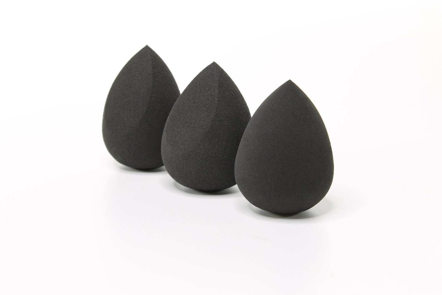 Three black makeup blending sponges arranged together, showcasing their unique shapes and soft texture for flawless makeup application.