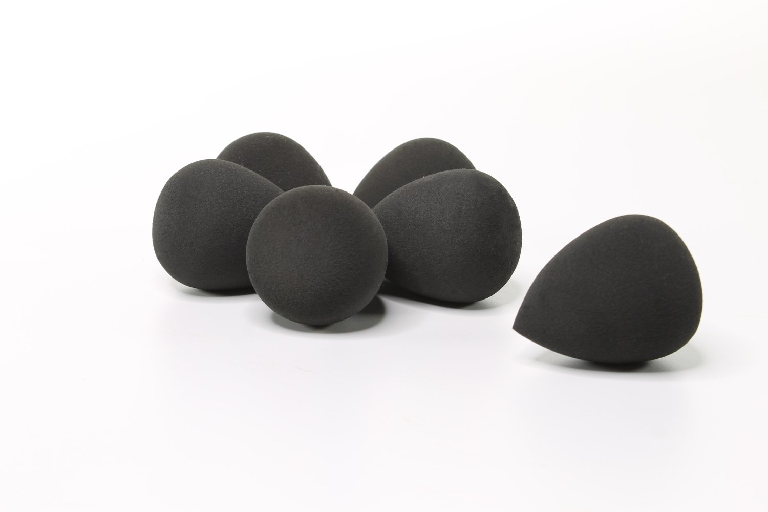 Three black makeup blending sponges arranged together, showcasing their unique shapes and soft texture for flawless makeup application.