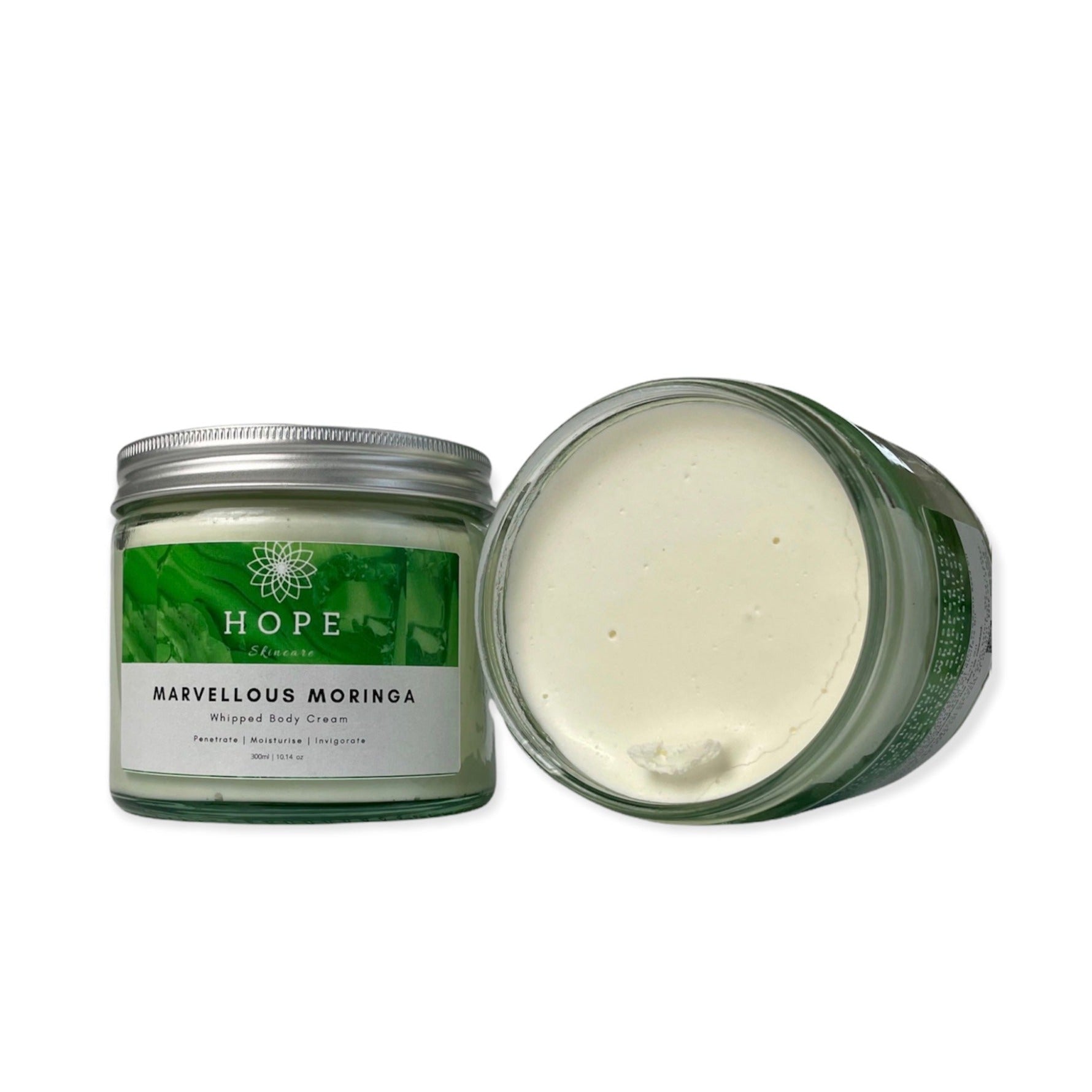 A jar of Marvellous Moringa Whipped Body Cream with a smooth, creamy texture, surrounded by Moringa leaves and Bergamot fruit.