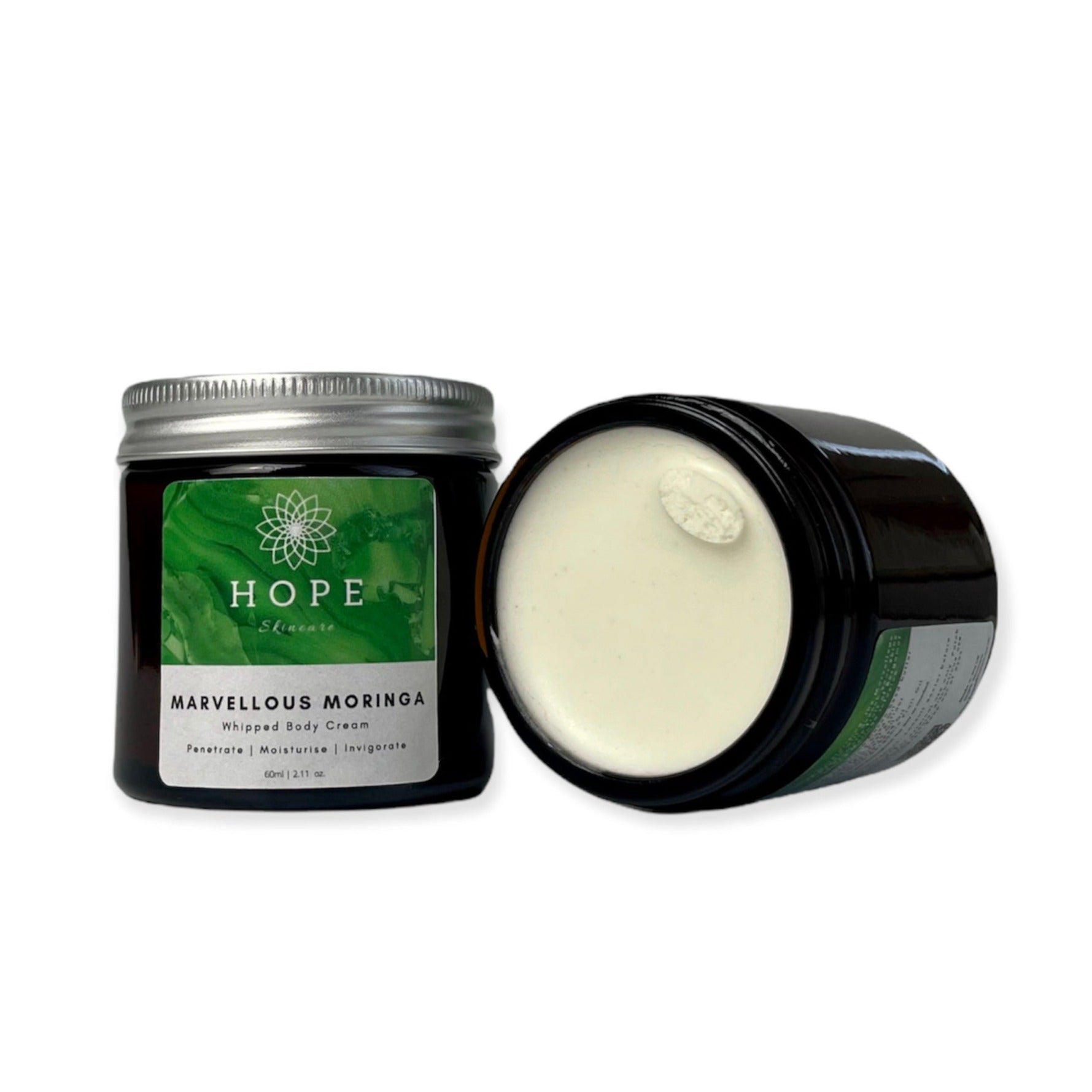 A jar of Marvellous Moringa Whipped Body Cream with a smooth, creamy texture, surrounded by Moringa leaves and Bergamot fruit.