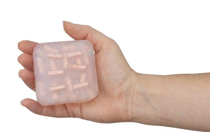 Monthly Comfort Burst Bar with essential oils and fizzing bath bomb pockets, displayed on a wooden soap dish.