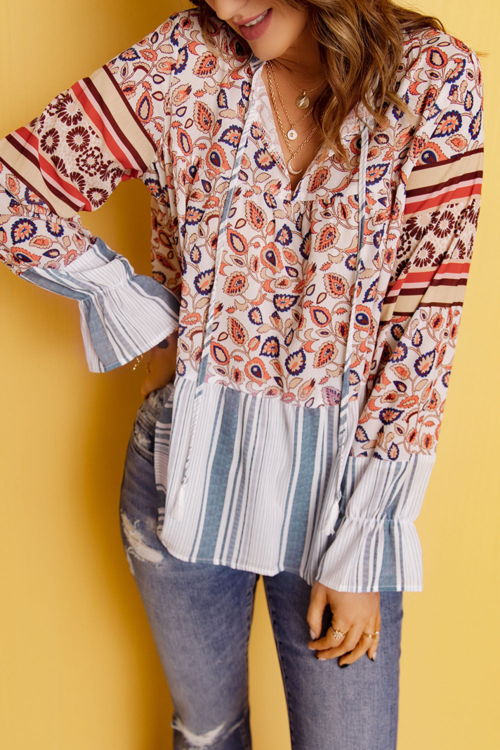 A vibrant multicolor loose fit floral striped blouse featuring a v-cut neckline, tie closure, and long flared sleeves, perfect for casual outings.