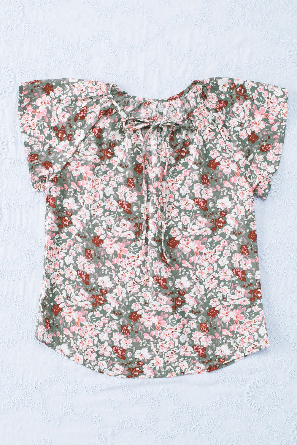 A vibrant multicolor V-neck blouse with short ruffled sleeves and a fluttering hem, showcasing an elegant fashion print.