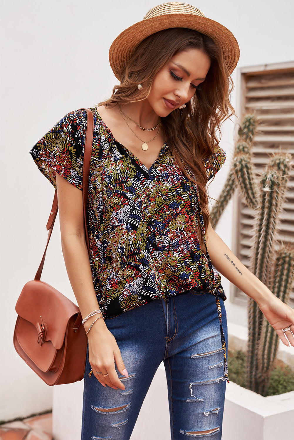 A vibrant multicolor V-neck blouse with short ruffled sleeves and a fluttering hem, showcasing an elegant fashion print.