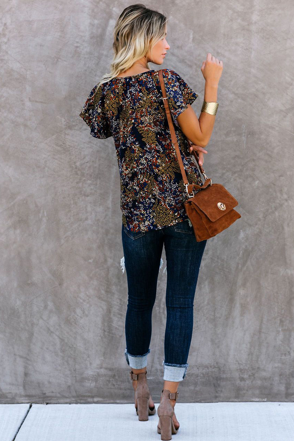 A vibrant multicolor V-neck blouse with short ruffled sleeves and a fluttering hem, showcasing an elegant fashion print.
