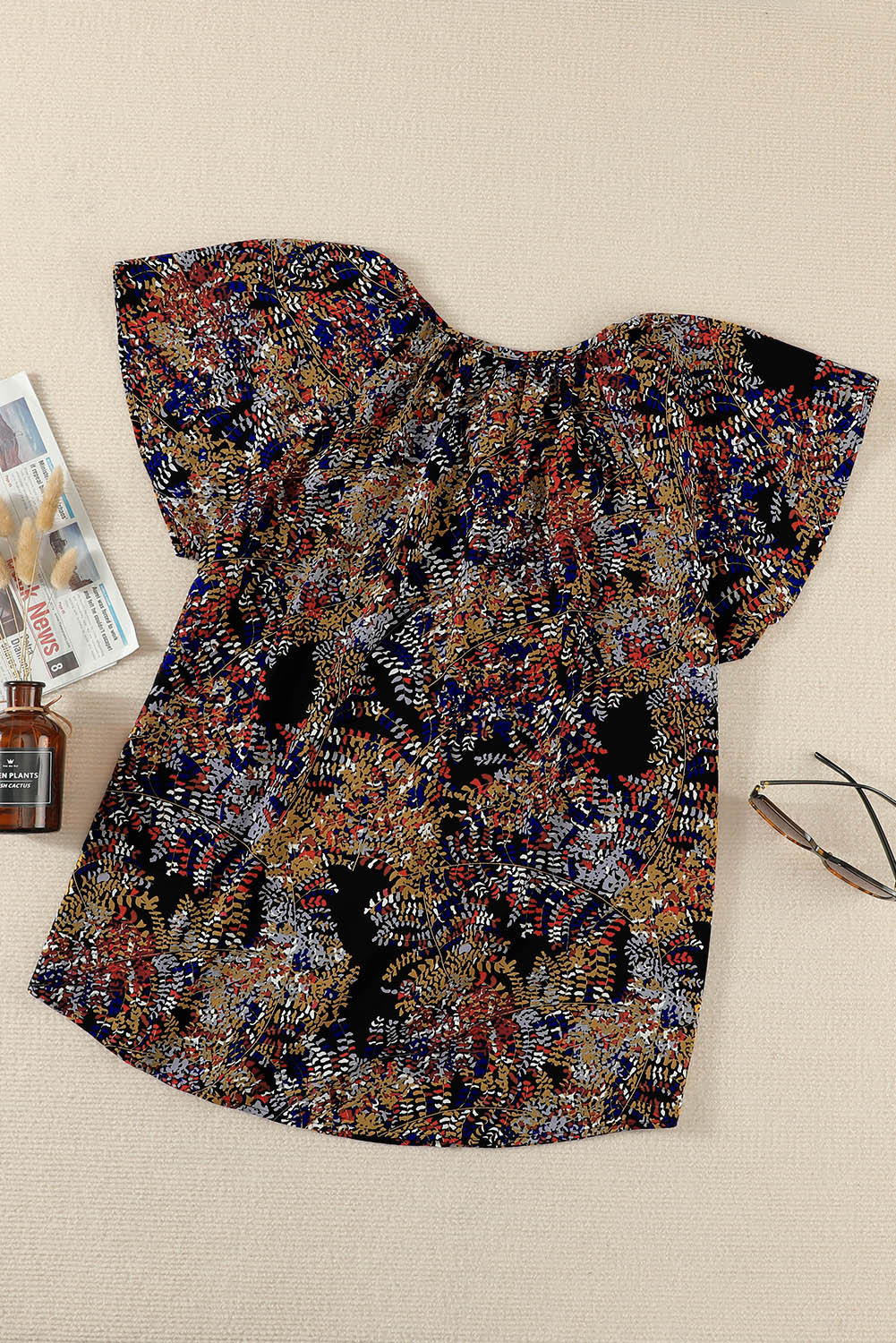 A vibrant multicolor V-neck blouse with short ruffled sleeves and a fluttering hem, showcasing an elegant fashion print.