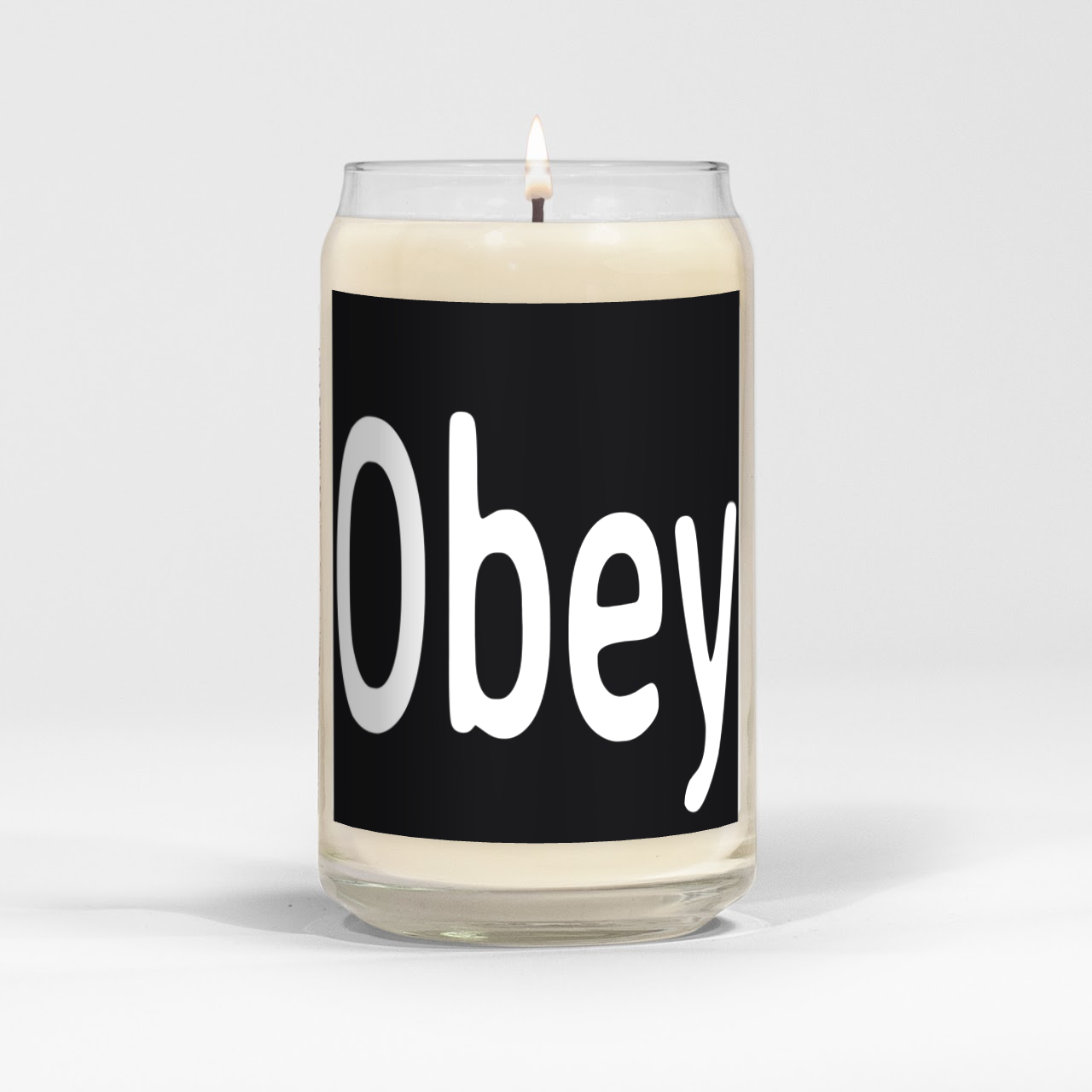 Obey candle in a clear vessel with a white label, showcasing its elegant design and natural soy wax blend.