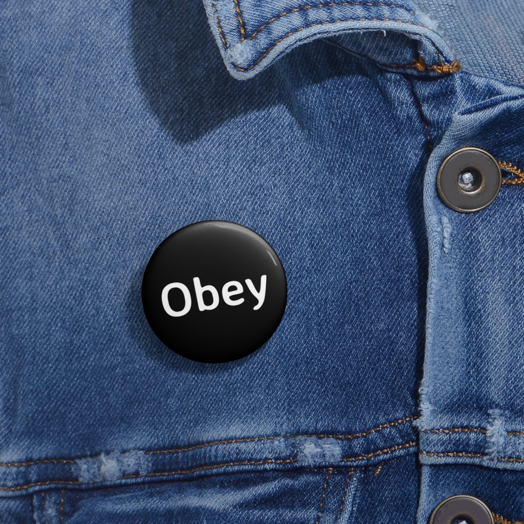Obey Pin Button featuring a lightweight metal design with a strong safety pin backing, available in three sizes.