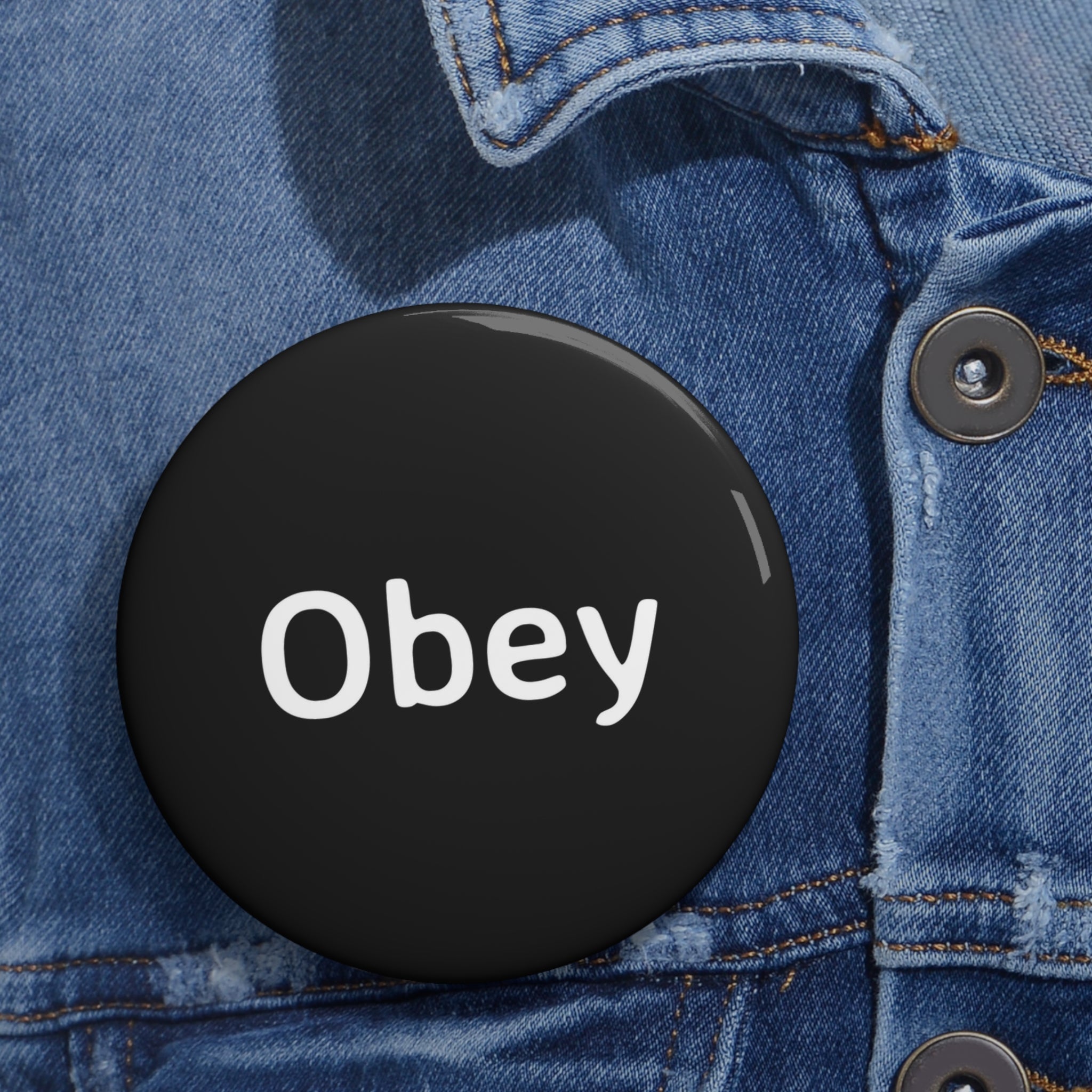 Obey Pin Button featuring a lightweight metal design with a strong safety pin backing, available in three sizes.
