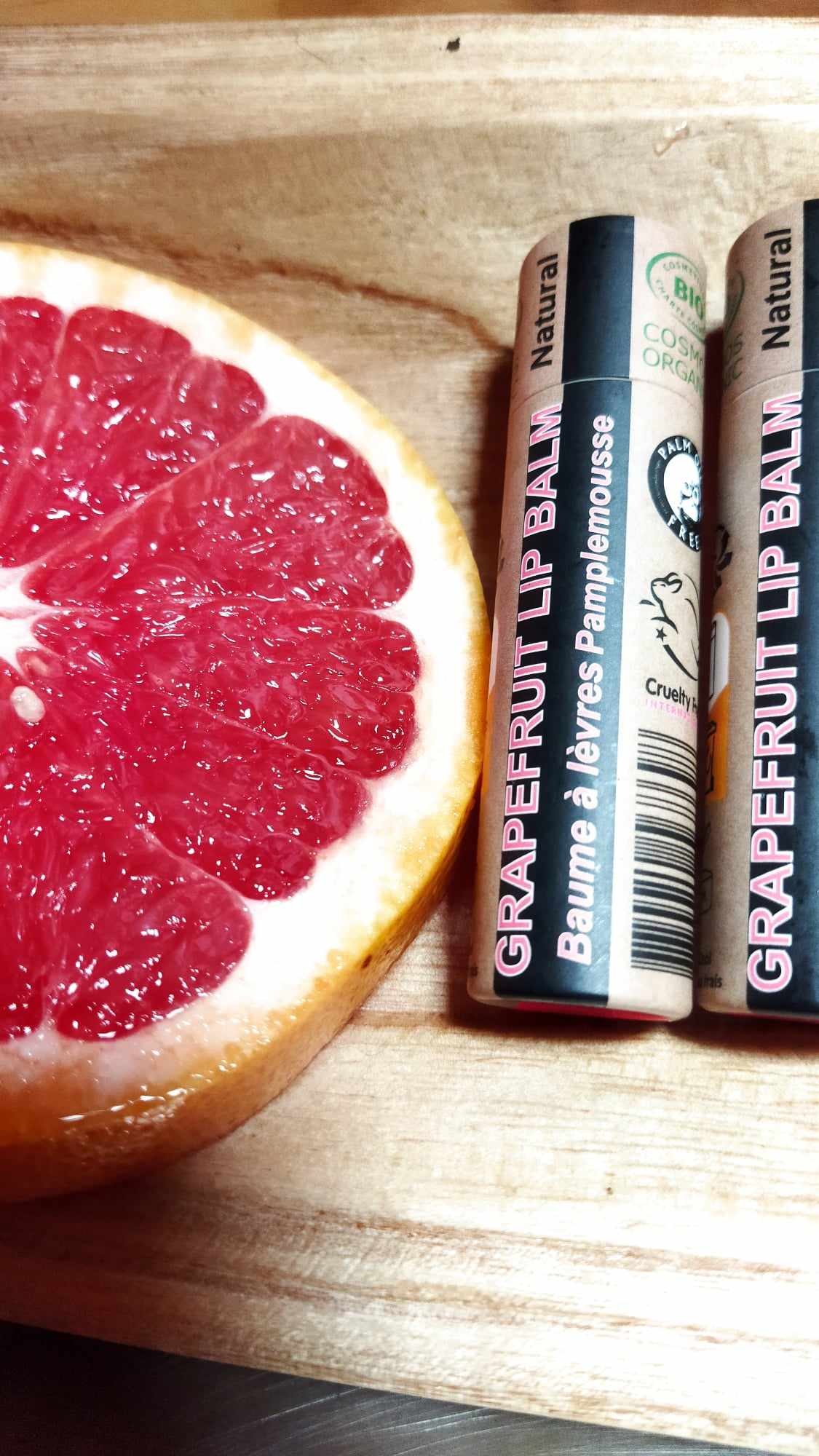 Organic Pink Grapefruit Lip Balm in a paper tube, showcasing its natural ingredients and eco-friendly packaging.