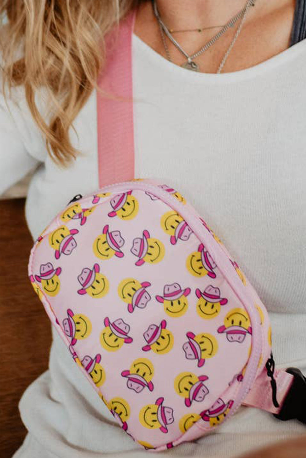 Pink crossbody bag featuring a cowboy hat and smile face print, with an adjustable buckle strap.