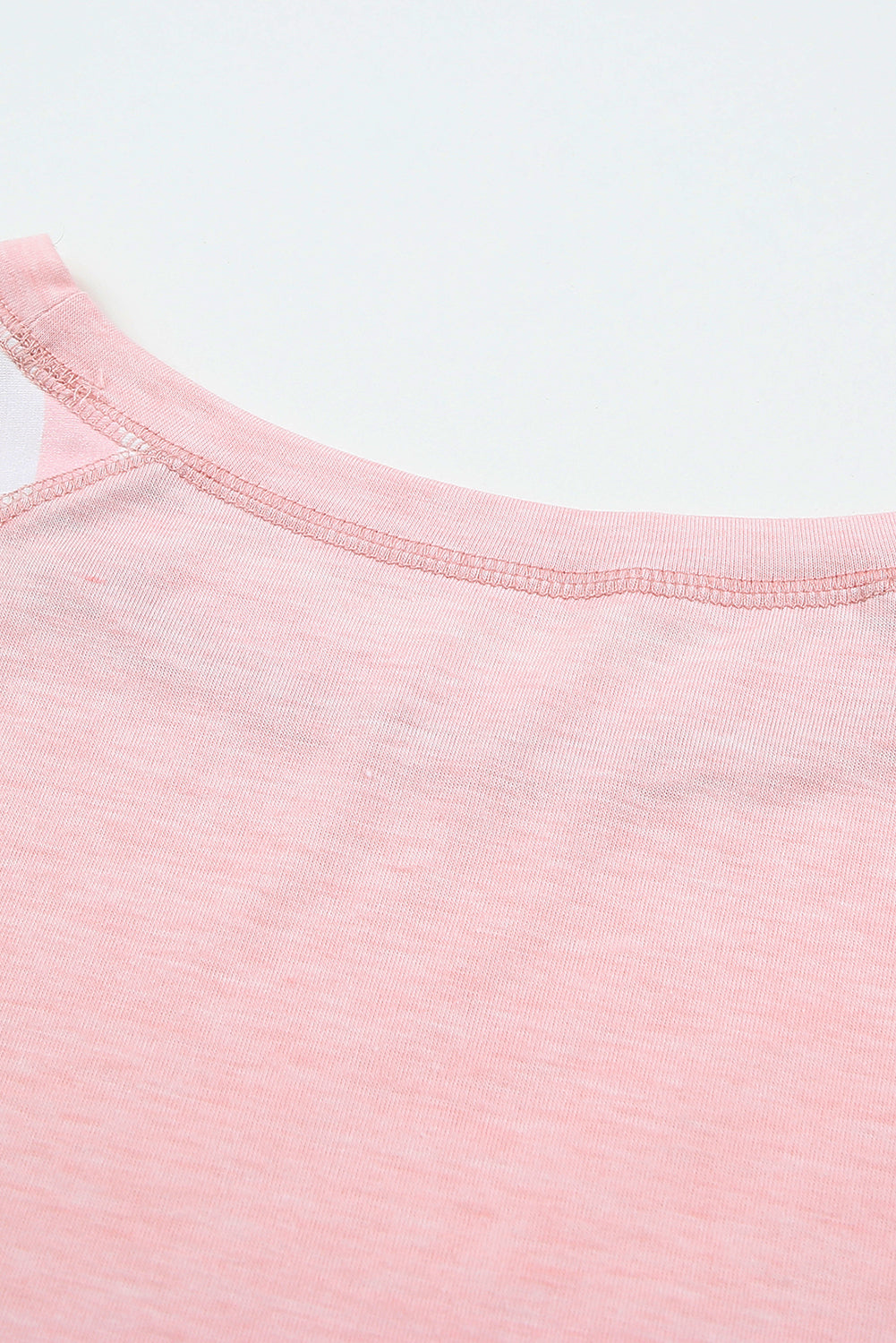 A stylish pink crewneck t-shirt featuring raglan sleeves with striped patchwork design, perfect for summer wear.