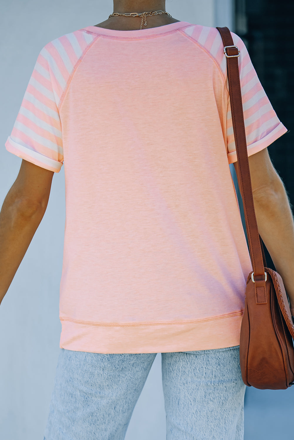 A stylish pink crewneck t-shirt featuring raglan sleeves with striped patchwork design, perfect for summer wear.