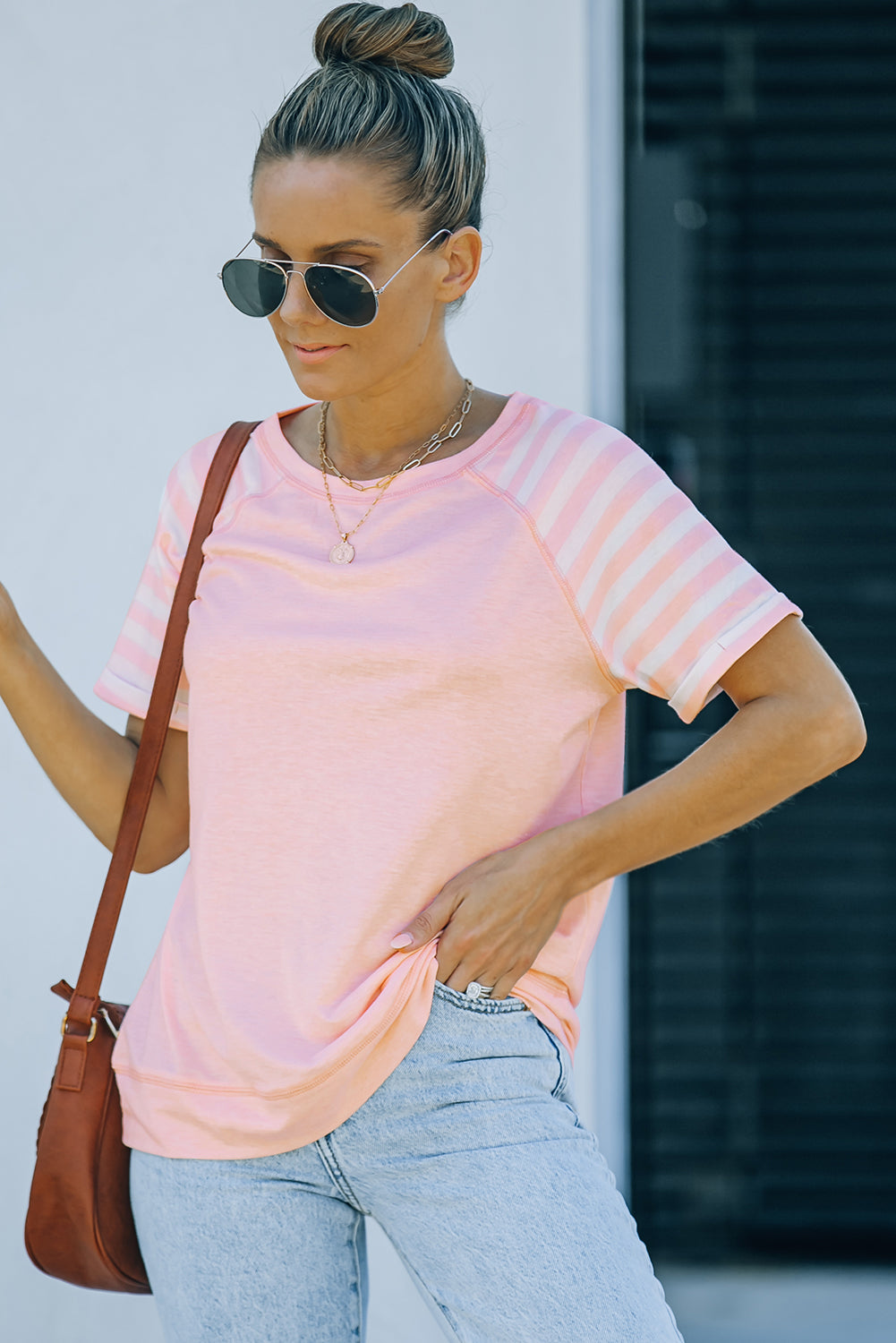 A stylish pink crewneck t-shirt featuring raglan sleeves with striped patchwork design, perfect for summer wear.