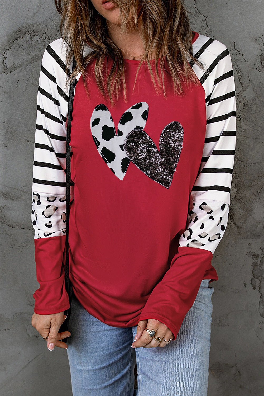 A vibrant red long sleeve top featuring double heart patches on the front, showcasing a stylish contrast design.