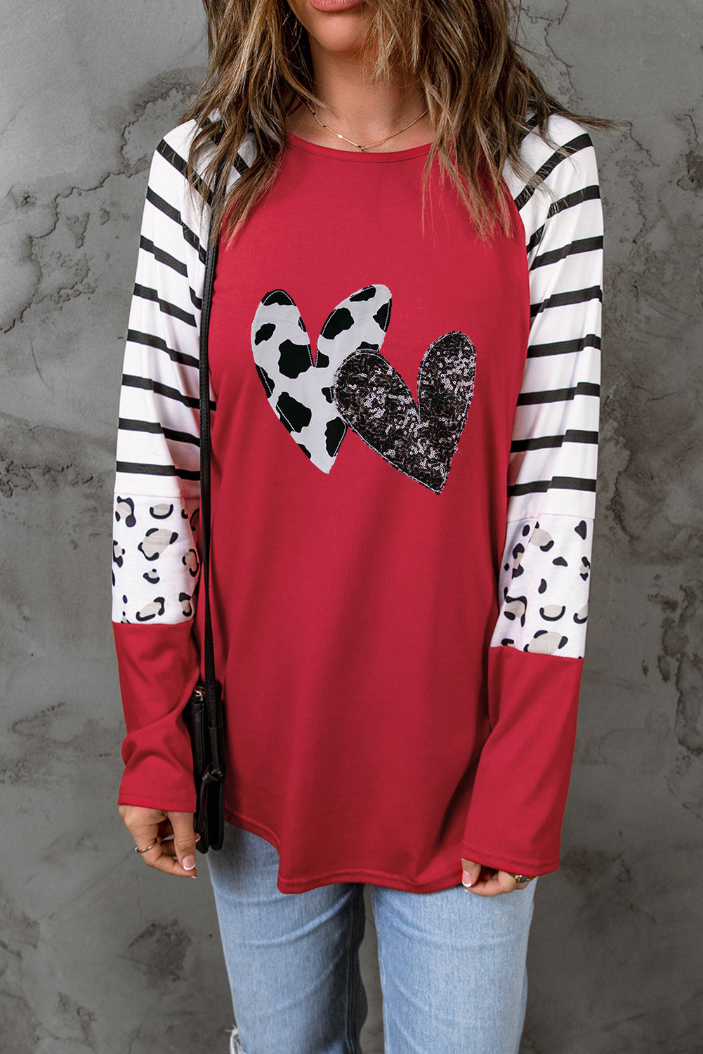 A vibrant red long sleeve top featuring double heart patches on the front, showcasing a stylish contrast design.