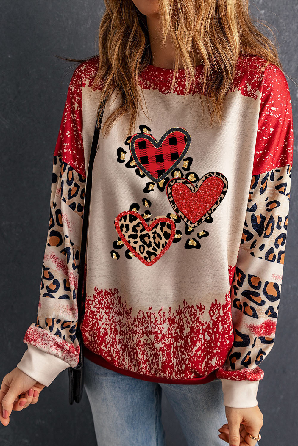 Red pullover sweatshirt featuring a heart-shaped leopard print design with a bleached effect, perfect for casual wear.