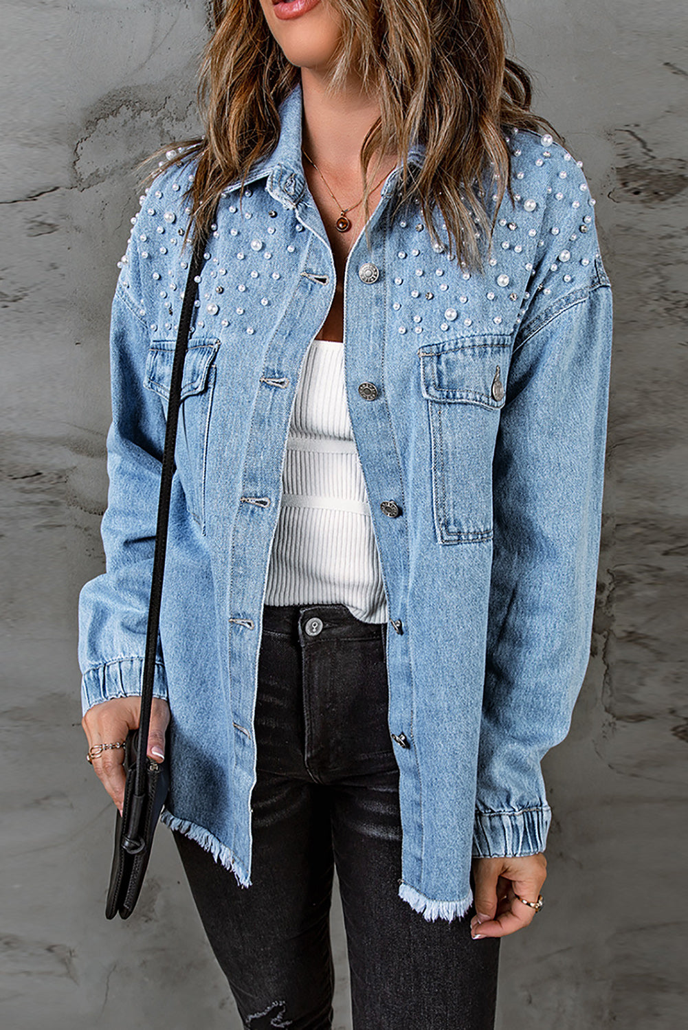 Sky blue denim shacket embellished with rhinestones and pearls, featuring a raw hemline and flap pockets.