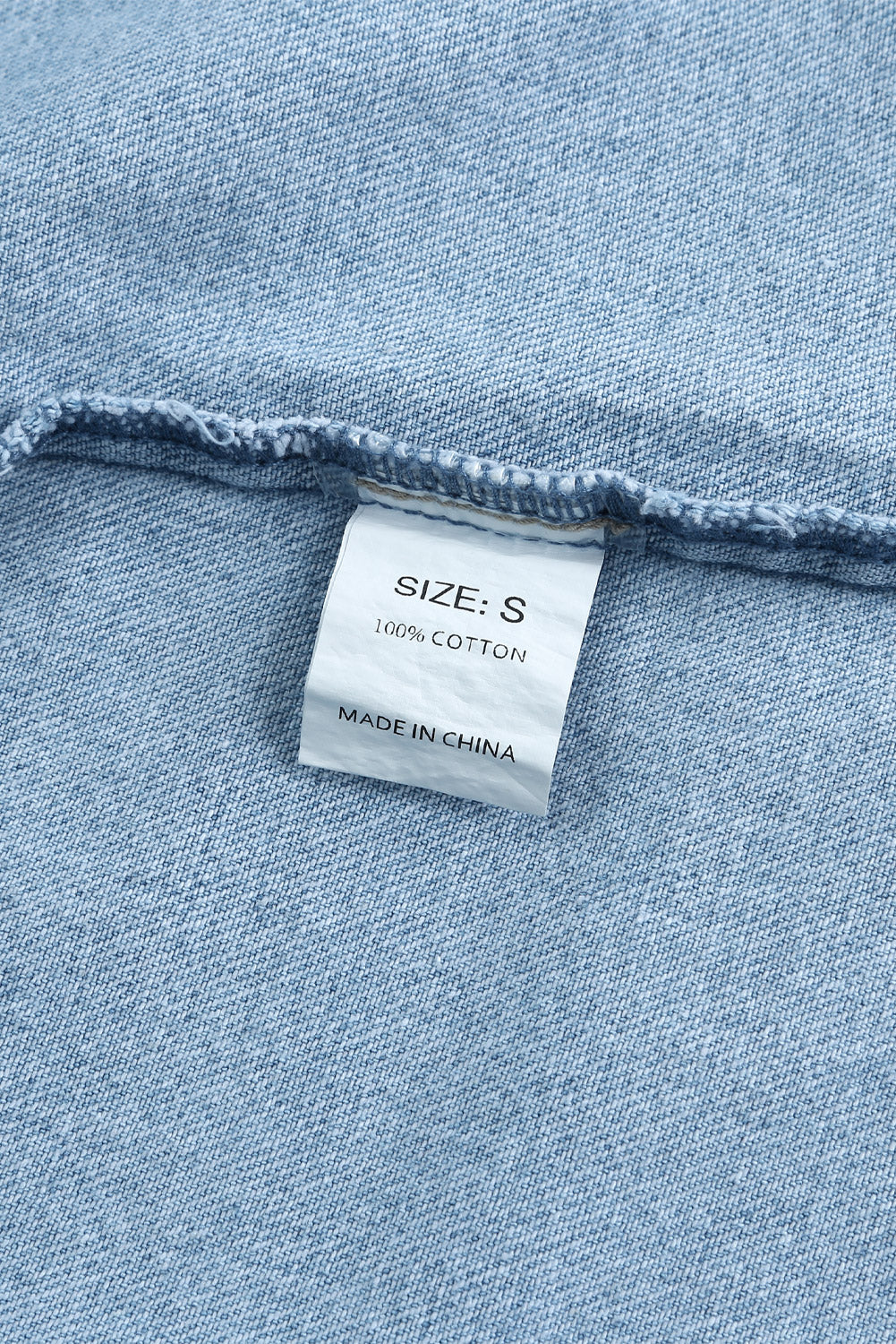 Sky blue denim shacket embellished with rhinestones and pearls, featuring a raw hemline and flap pockets.