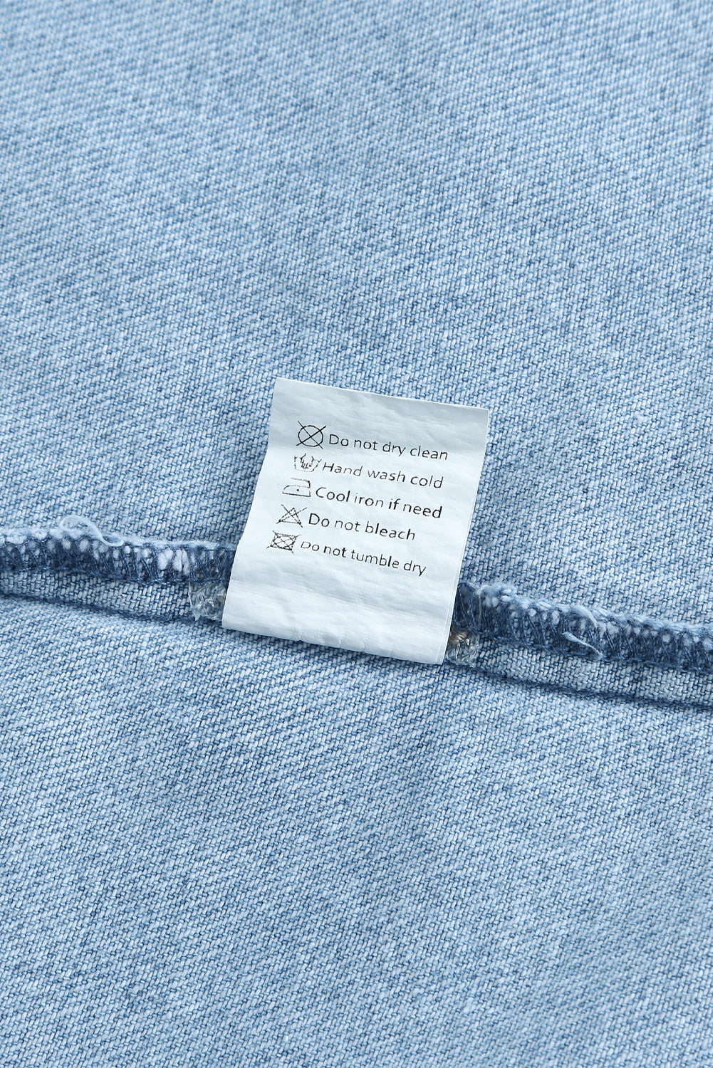 Sky blue denim shacket embellished with rhinestones and pearls, featuring a raw hemline and flap pockets.