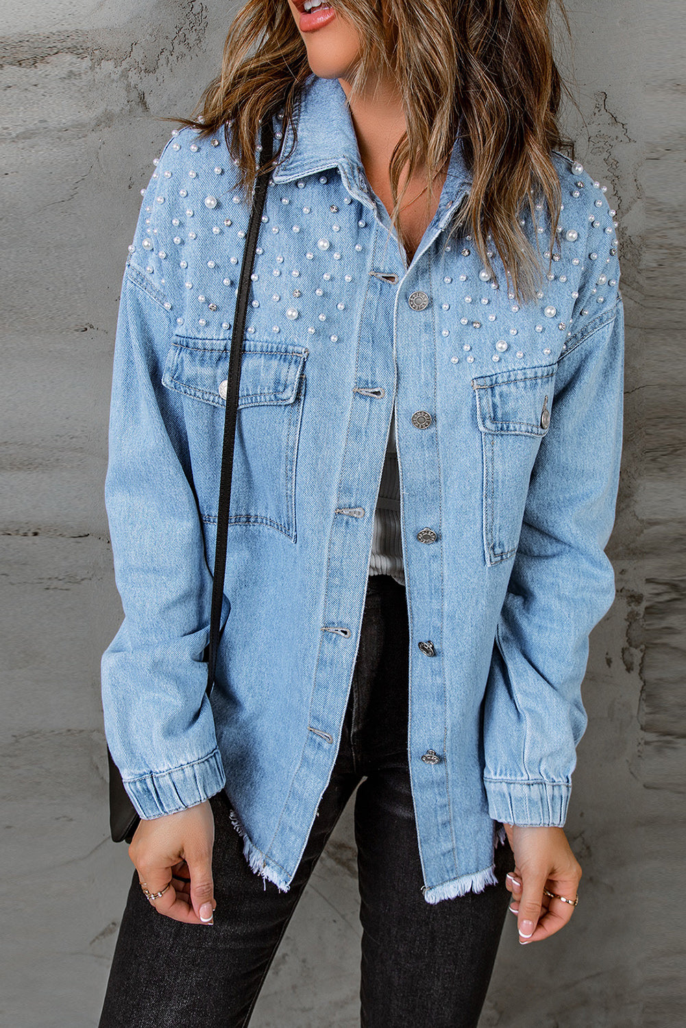 Sky blue denim shacket embellished with rhinestones and pearls, featuring a raw hemline and flap pockets.