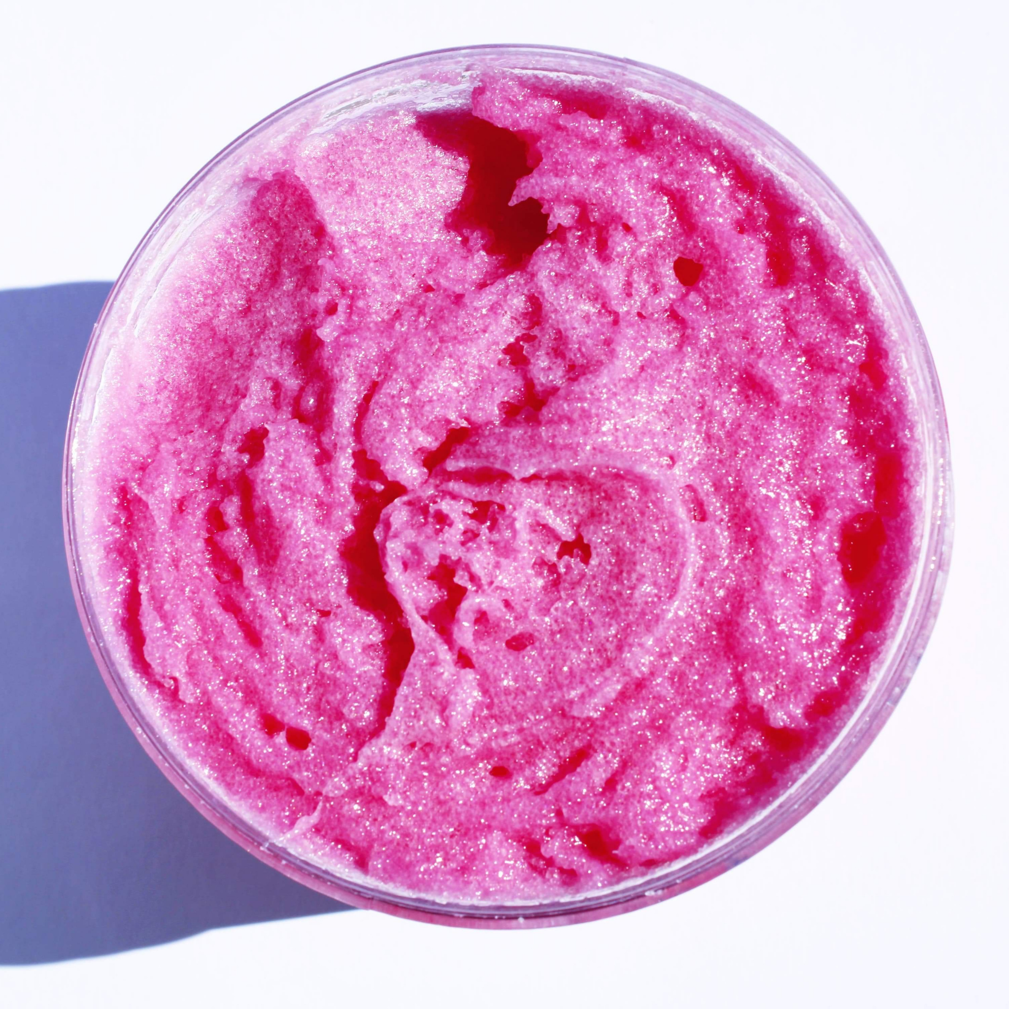 A jar of Strawberry Sugar Scrub with a creamy texture, surrounded by fresh strawberries and sugar granules, showcasing its natural ingredients.