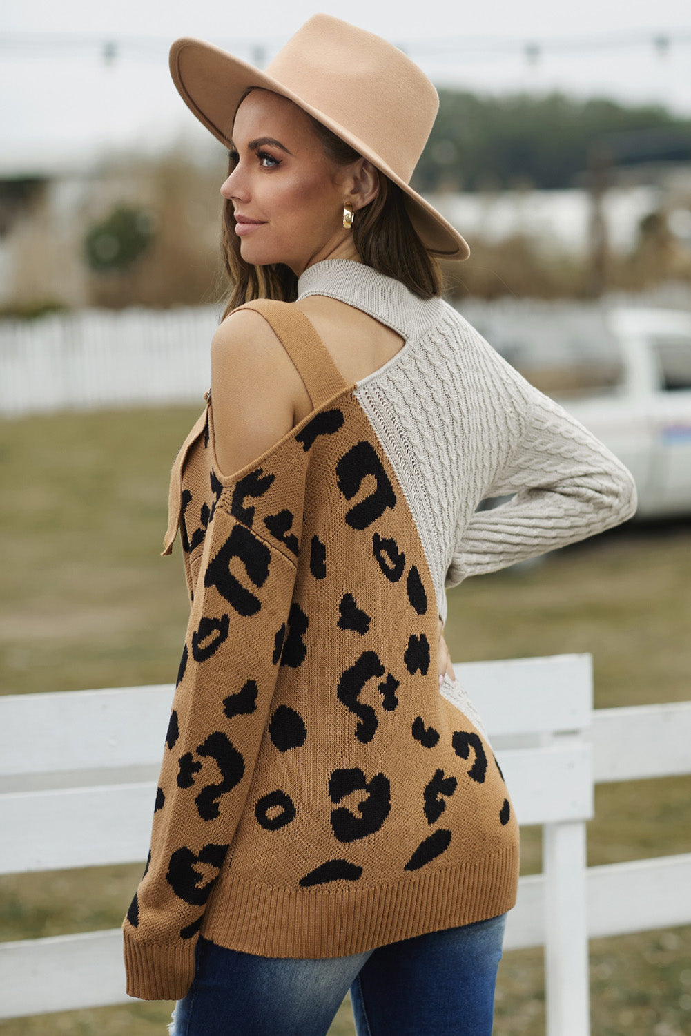 A stylish white asymmetrical sweater featuring a high neck, cold shoulder design, and buckle strap, perfect for chic outfits.