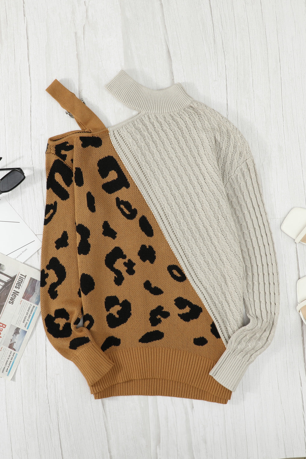 A stylish white asymmetrical sweater featuring a high neck, cold shoulder design, and buckle strap, perfect for chic outfits.