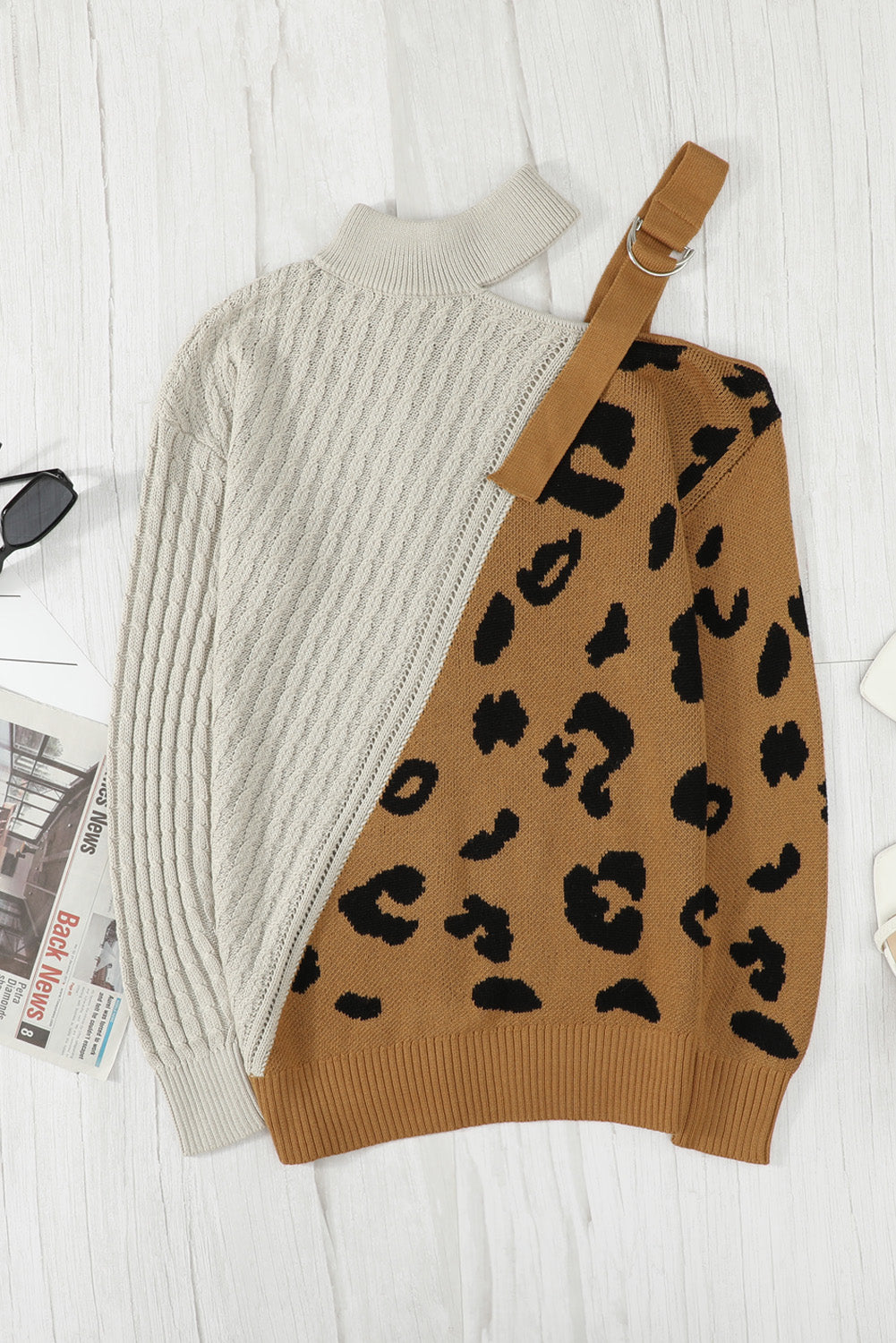 A stylish white asymmetrical sweater featuring a high neck, cold shoulder design, and buckle strap, perfect for chic outfits.