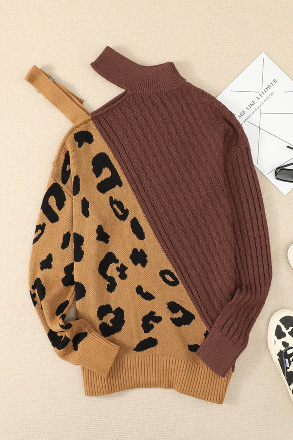 A stylish white asymmetrical sweater featuring a high neck, cold shoulder design, and buckle strap, perfect for chic outfits.