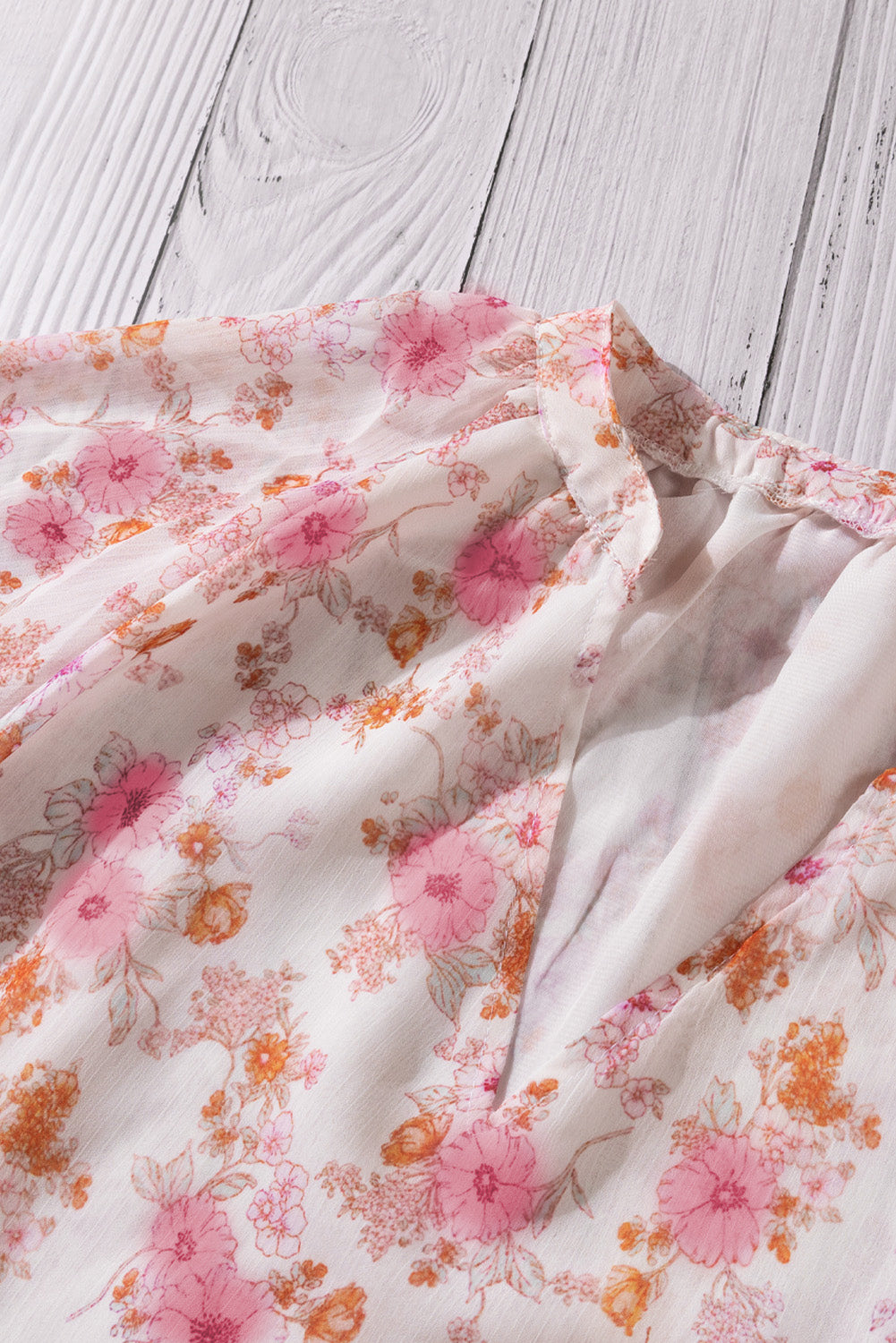 A stylish white top featuring a floral print, V-neckline, and long puff sleeves, perfect for casual and formal occasions.