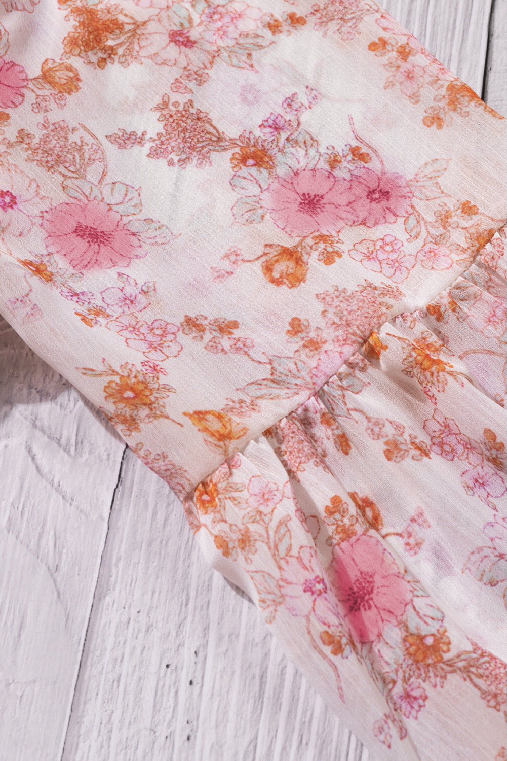 A stylish white top featuring a floral print, V-neckline, and long puff sleeves, perfect for casual and formal occasions.