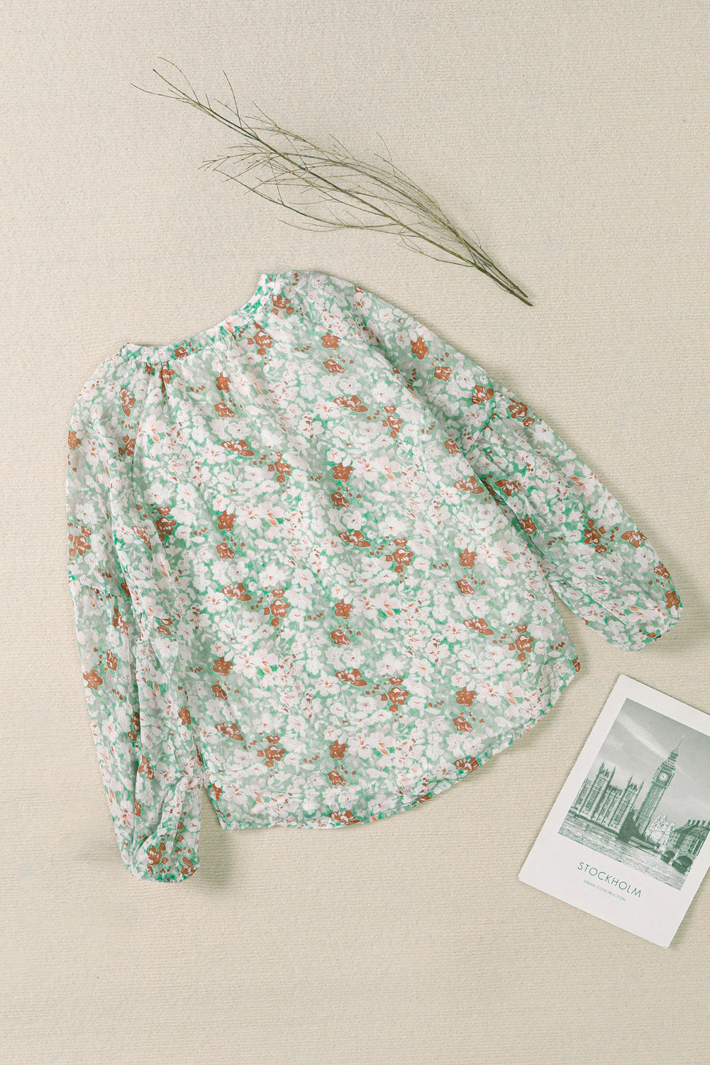 A stylish white top featuring a floral print, V-neckline, and long puff sleeves, perfect for casual and formal occasions.