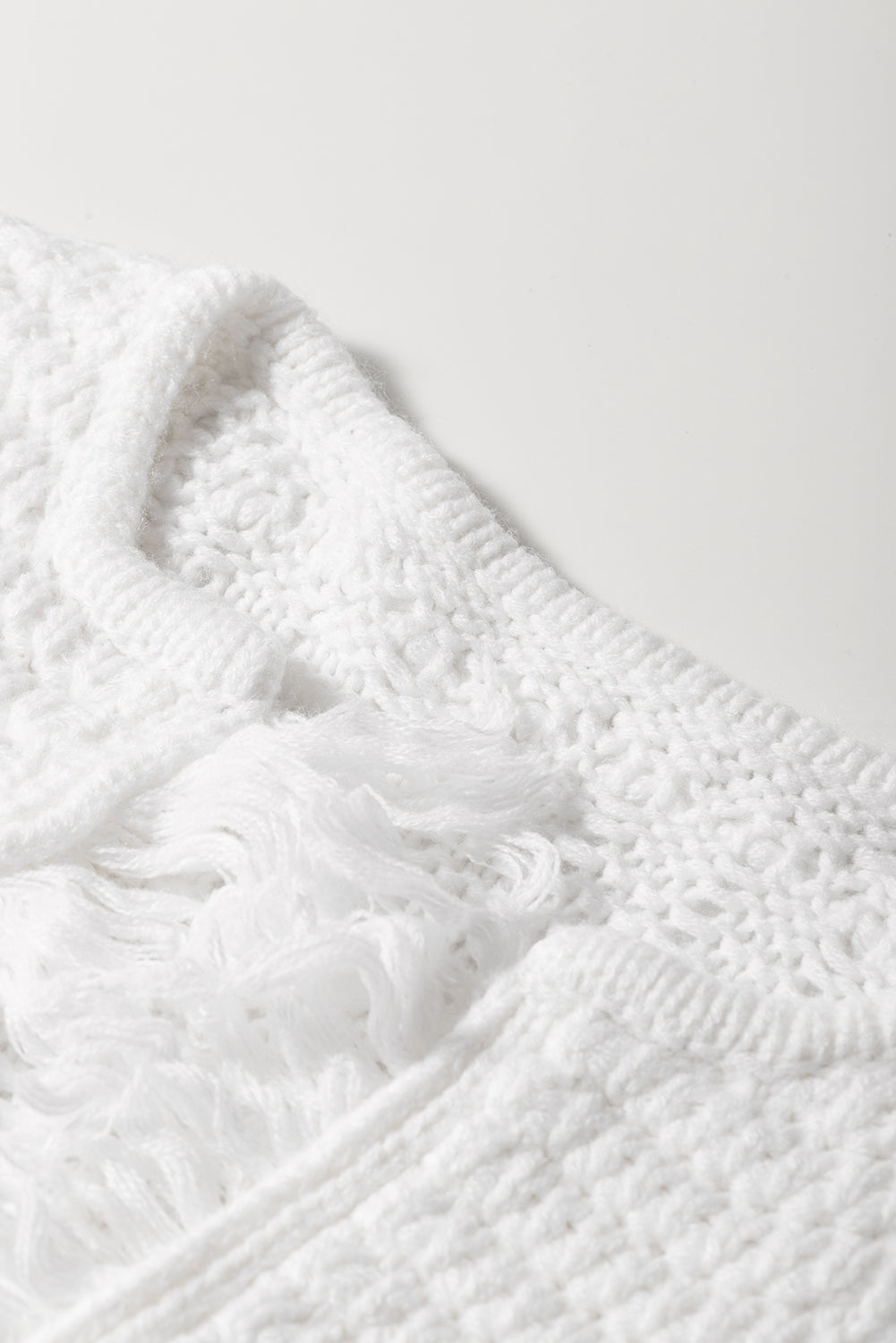 A stylish white long cardigan with fringed edges and open front, featuring two pockets, perfect for layering and adding elegance to any outfit.