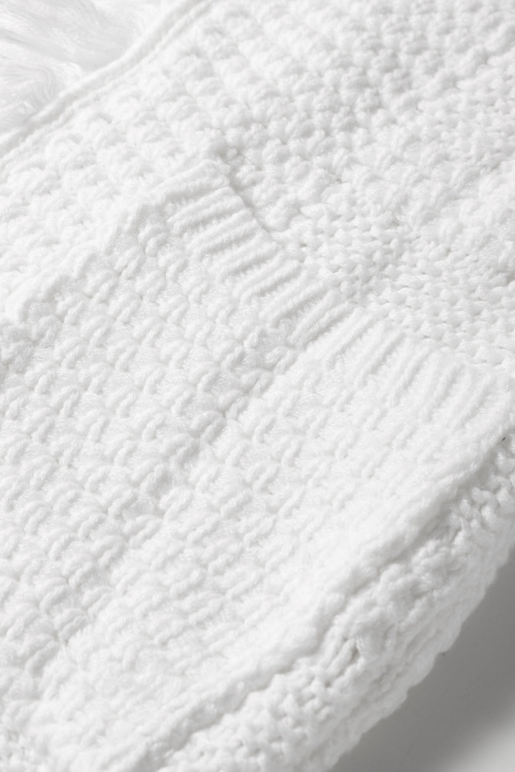 A stylish white long cardigan with fringed edges and open front, featuring two pockets, perfect for layering and adding elegance to any outfit.