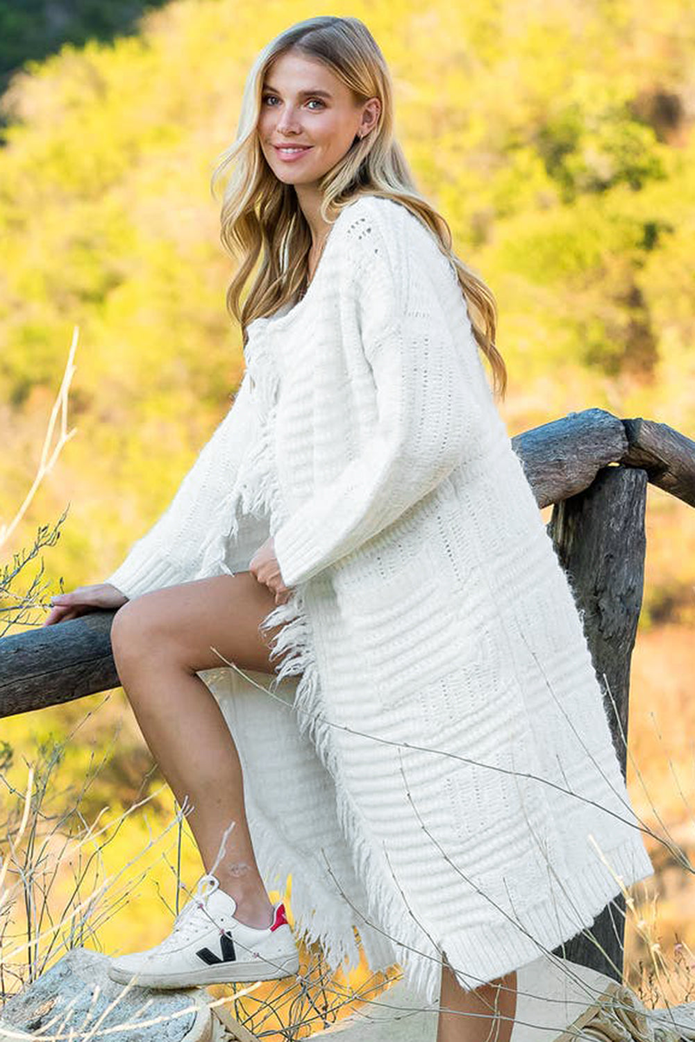 A stylish white long cardigan with fringed edges and open front, featuring two pockets, perfect for layering and adding elegance to any outfit.