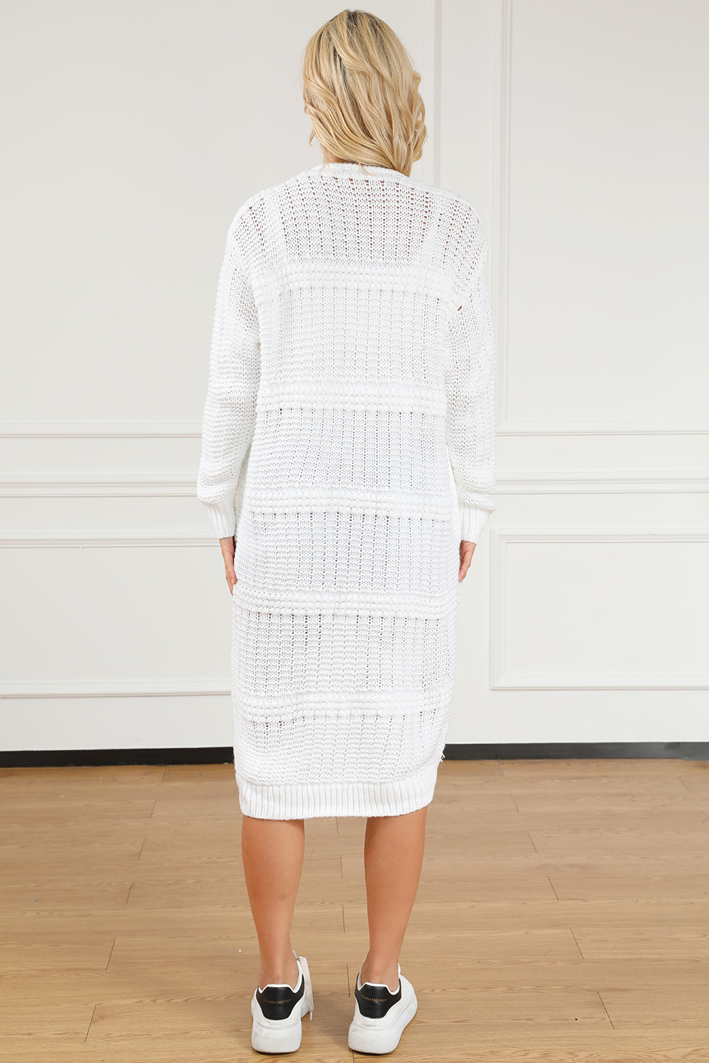 A stylish white long cardigan with fringed edges and open front, featuring two pockets, perfect for layering and adding elegance to any outfit.