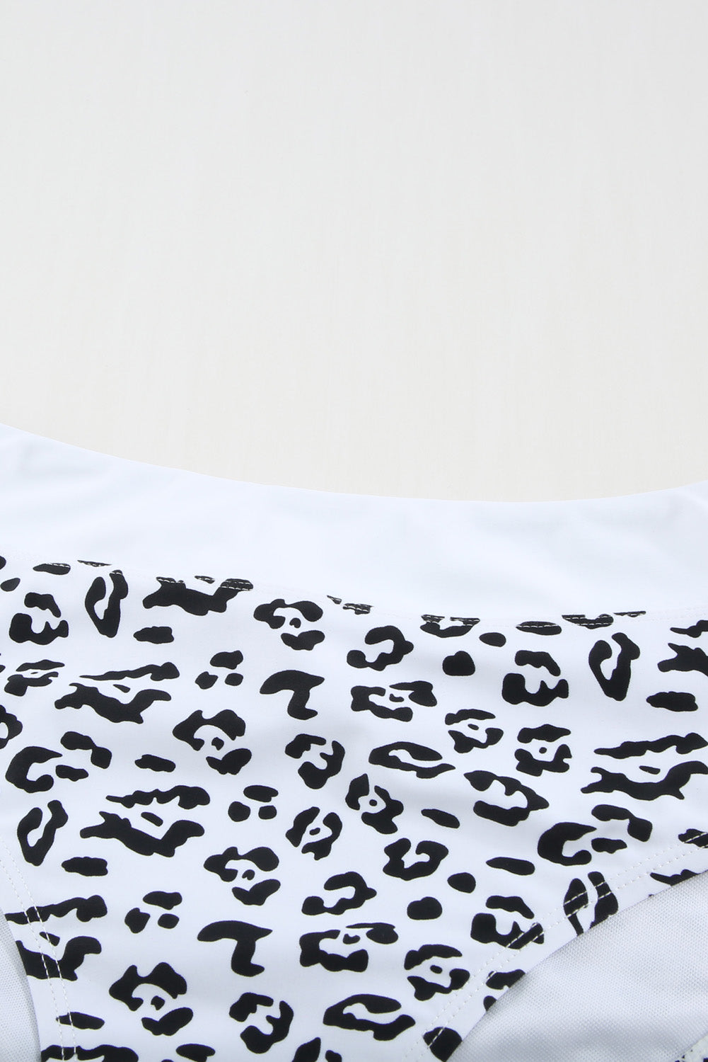 White leopard print criss cross bikini set featuring a deep V neckline and criss-cross back design, perfect for summer beach outings.